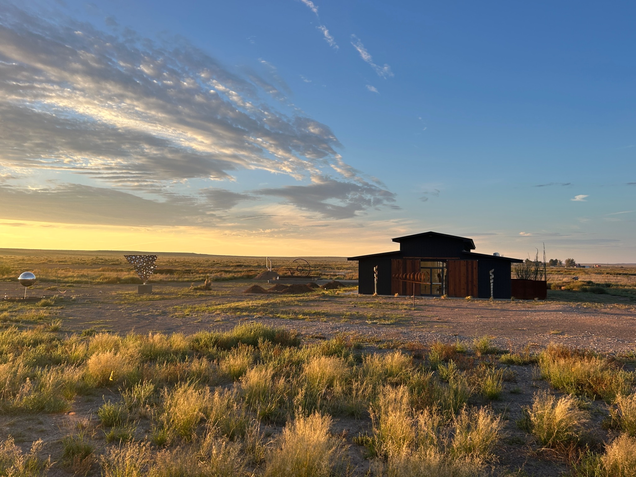 The Old Stables black gallery building, wooden doors, and outdoor metal sculptures against the Marfa prairie